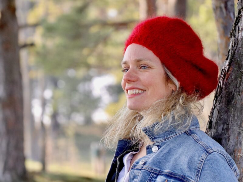 mannequin avec béret mohair rubis de profile veste en jean contre un arbre